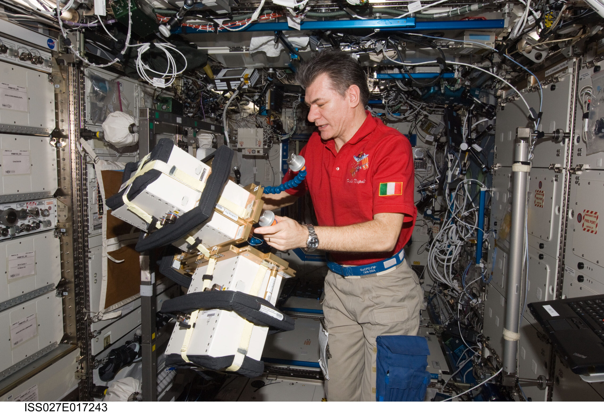 Paolo Nespoli, astronauta de la ESA, sujeta con las dos manos un bloque de cajas blancas rectangulares, los detectores del experimento ALTEA, montado sobre un soporte dentro del laboratorio Destiny de la Estación Espacial Internacional, entre paneles cubiertos de cables, etiquetas y bolsas de equipo.