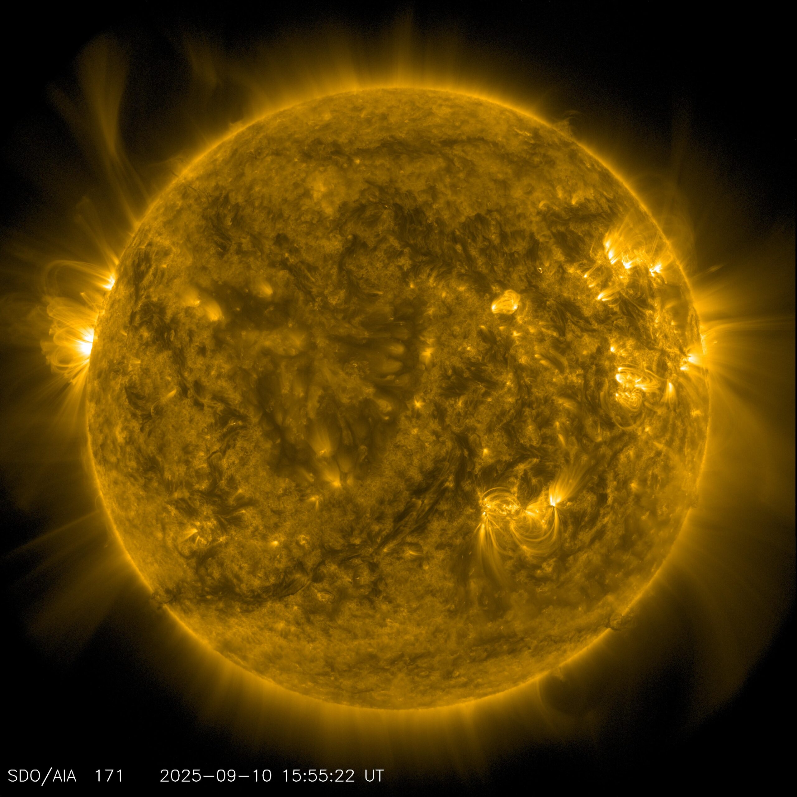 El disco completo del Sol sobre fondo negro, en tonos dorados y anaranjados. La superficie aparece veteada de filamentos oscuros y de zonas brillantes, y del borde salen arcos y penachos de material que se curvan sobre el fondo negro. Abajo a la izquierda, un rótulo impreso en la imagen indica el instrumento y la fecha de la toma.