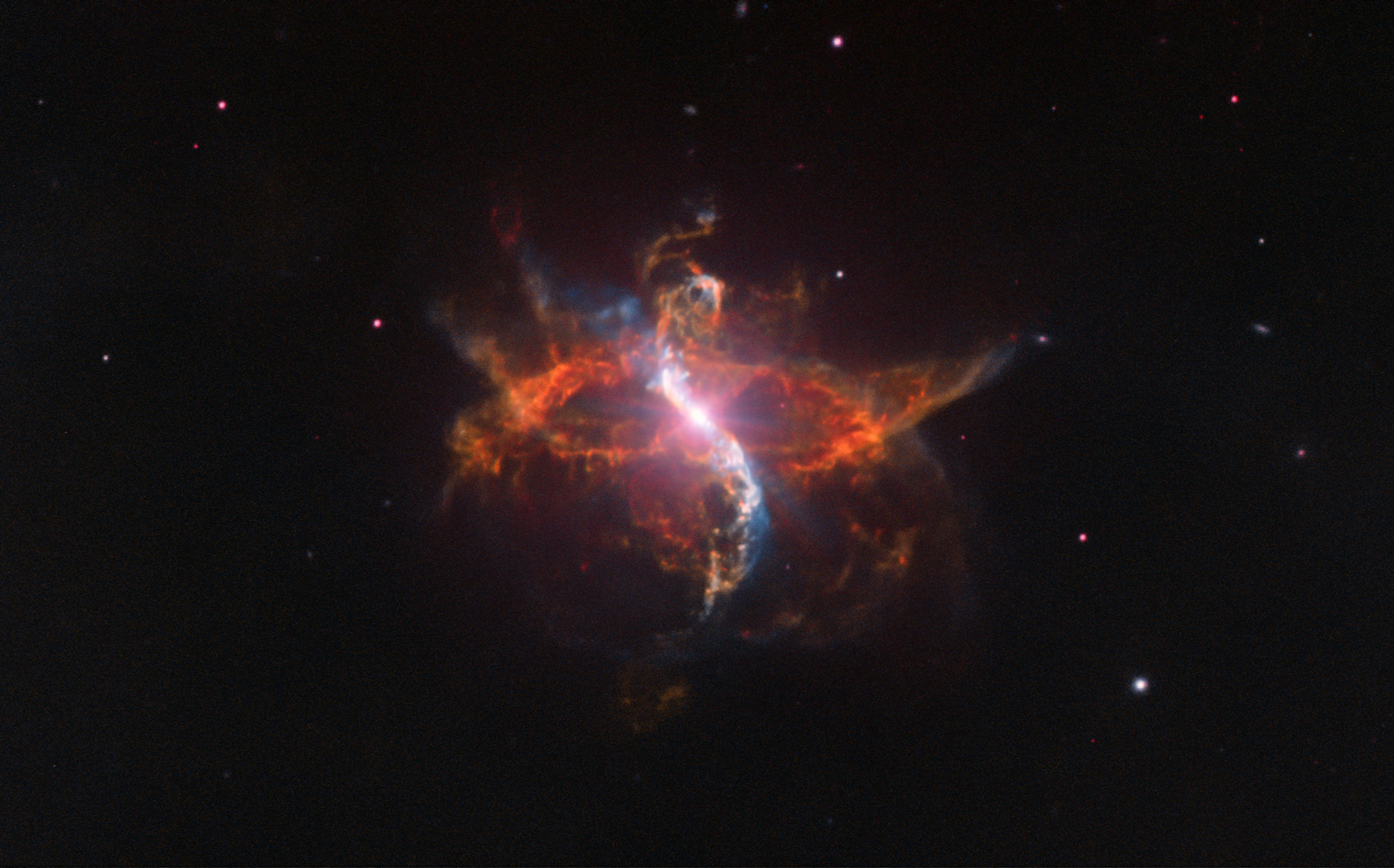 Imagen del sistema binario R Aquarii tomada con el Very Large Telescope: un punto de luz central muy brillante rodeado de filamentos y burbujas de gas rojizo que se abren en forma de ese, sobre un fondo negro con estrellas dispersas.