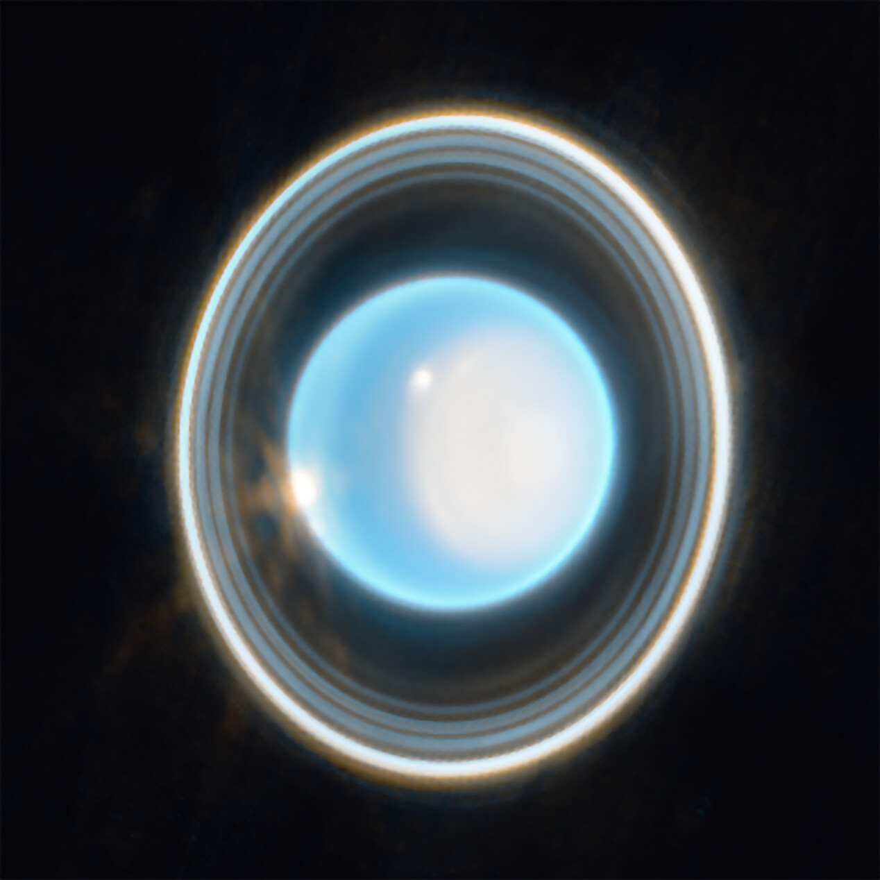 El planeta Urano, de color azul claro sobre fondo negro, con una gran mancha blanca en su lado derecho y dos puntos blancos brillantes, rodeado por un sistema de anillos finos y concéntricos dispuestos en vertical.